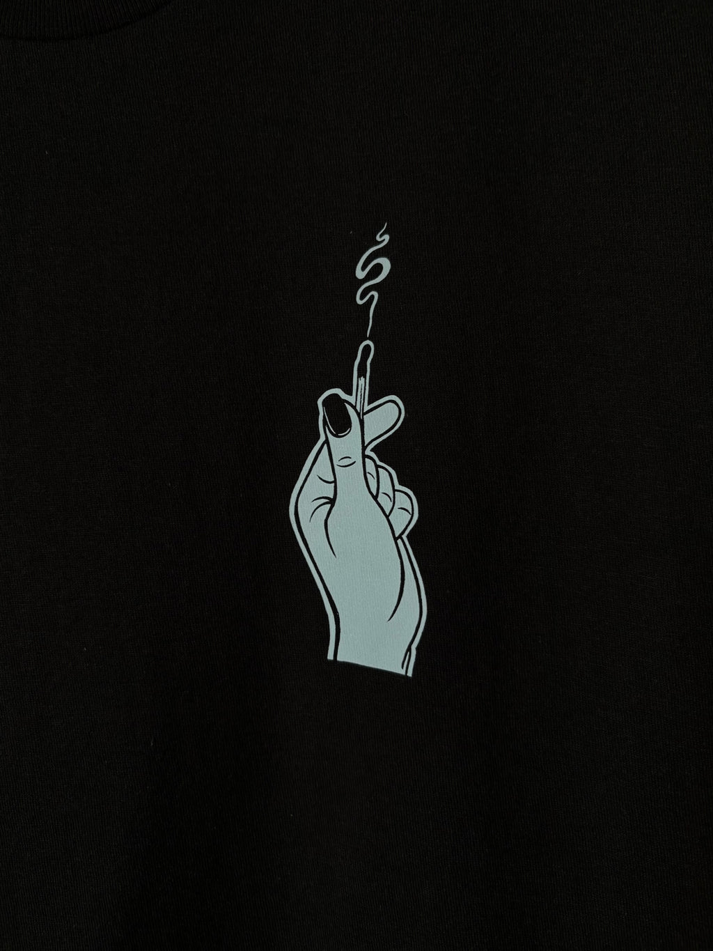 a closer look at the hand holding the burnt match, printed as a club patch on the front of a black t-shirt