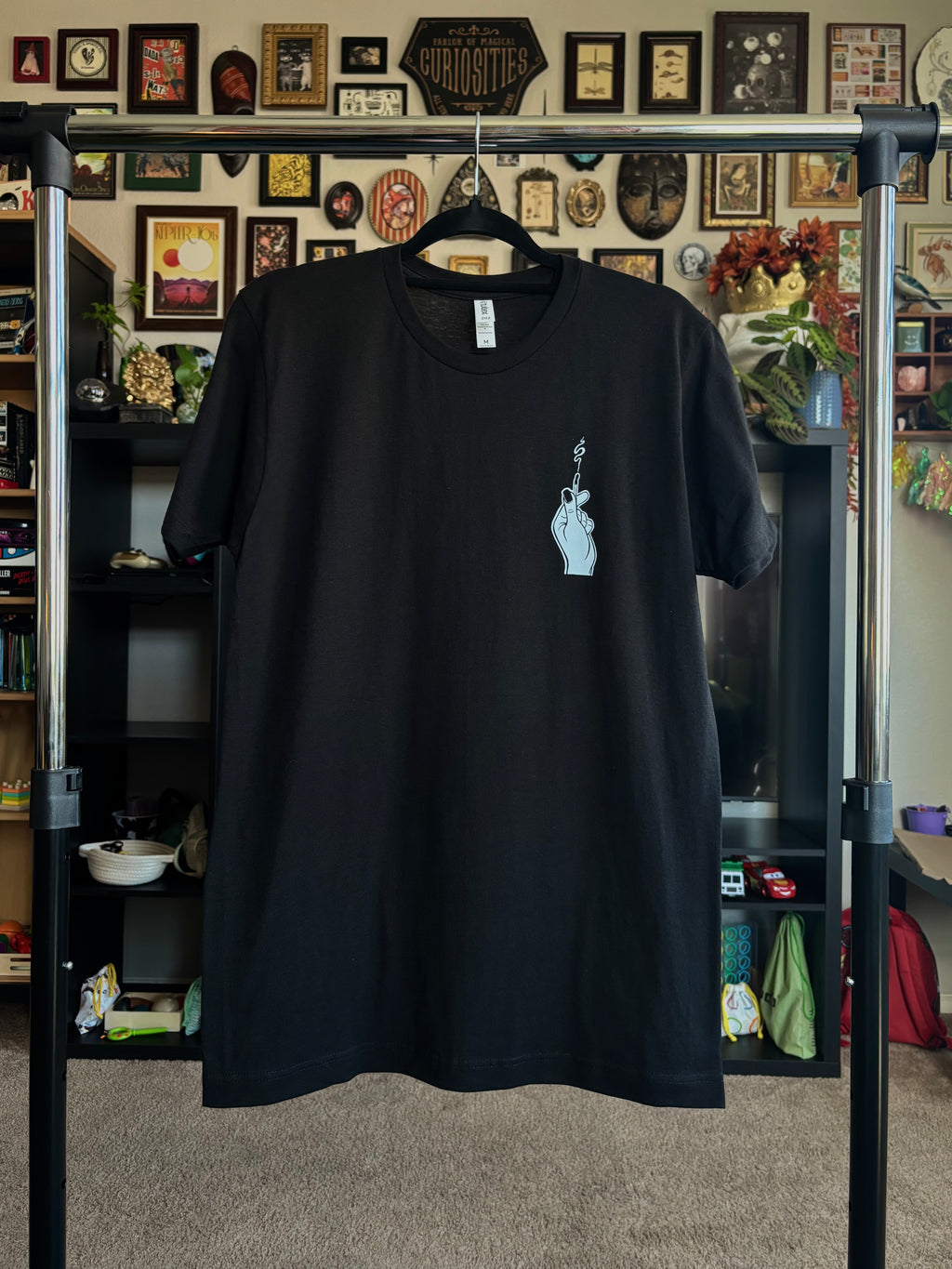 black tee hanging to show the club patch of the hand holding the match on the front