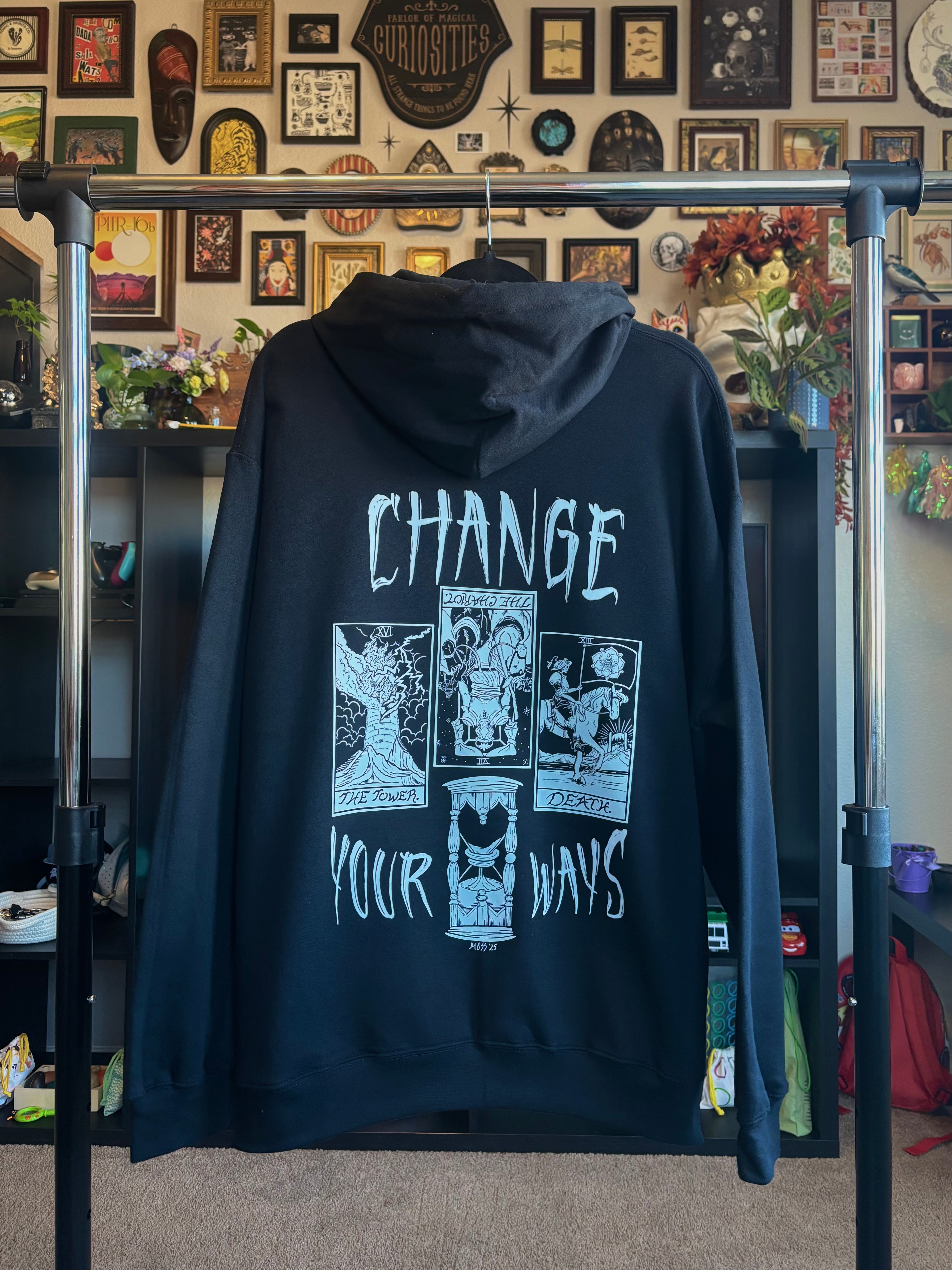 black hoodie with the Change Your Ways tarot inspired design hanging on a rack to show the full back print