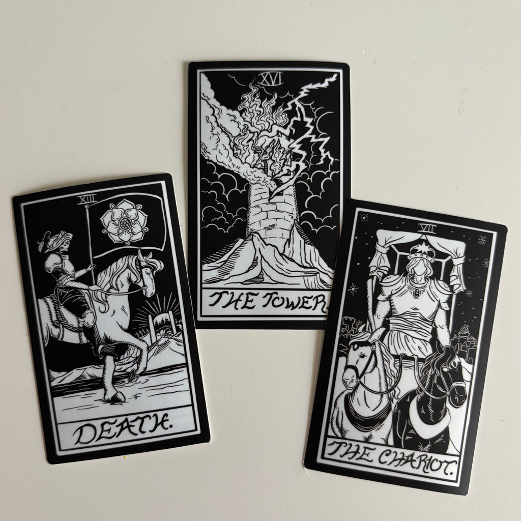 three black and white stickers of the tarot card designs for Death, The Tower, and The Chariot