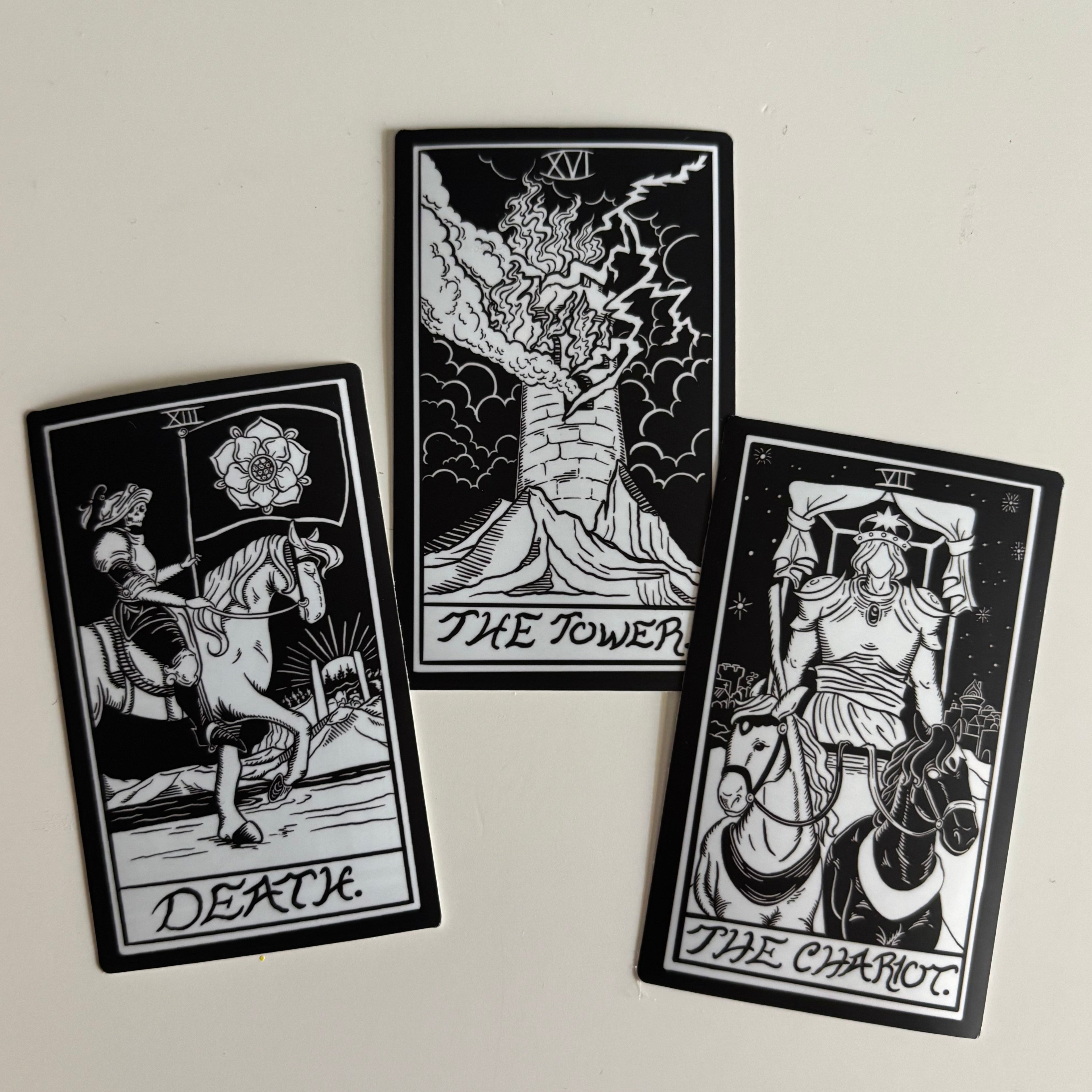 three black and white stickers of the tarot card designs for Death, The Tower, and The Chariot