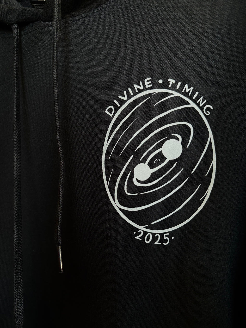 closeup look at the Divine Timing Binary Star badge printed as a club patch on the front of a black hoodie