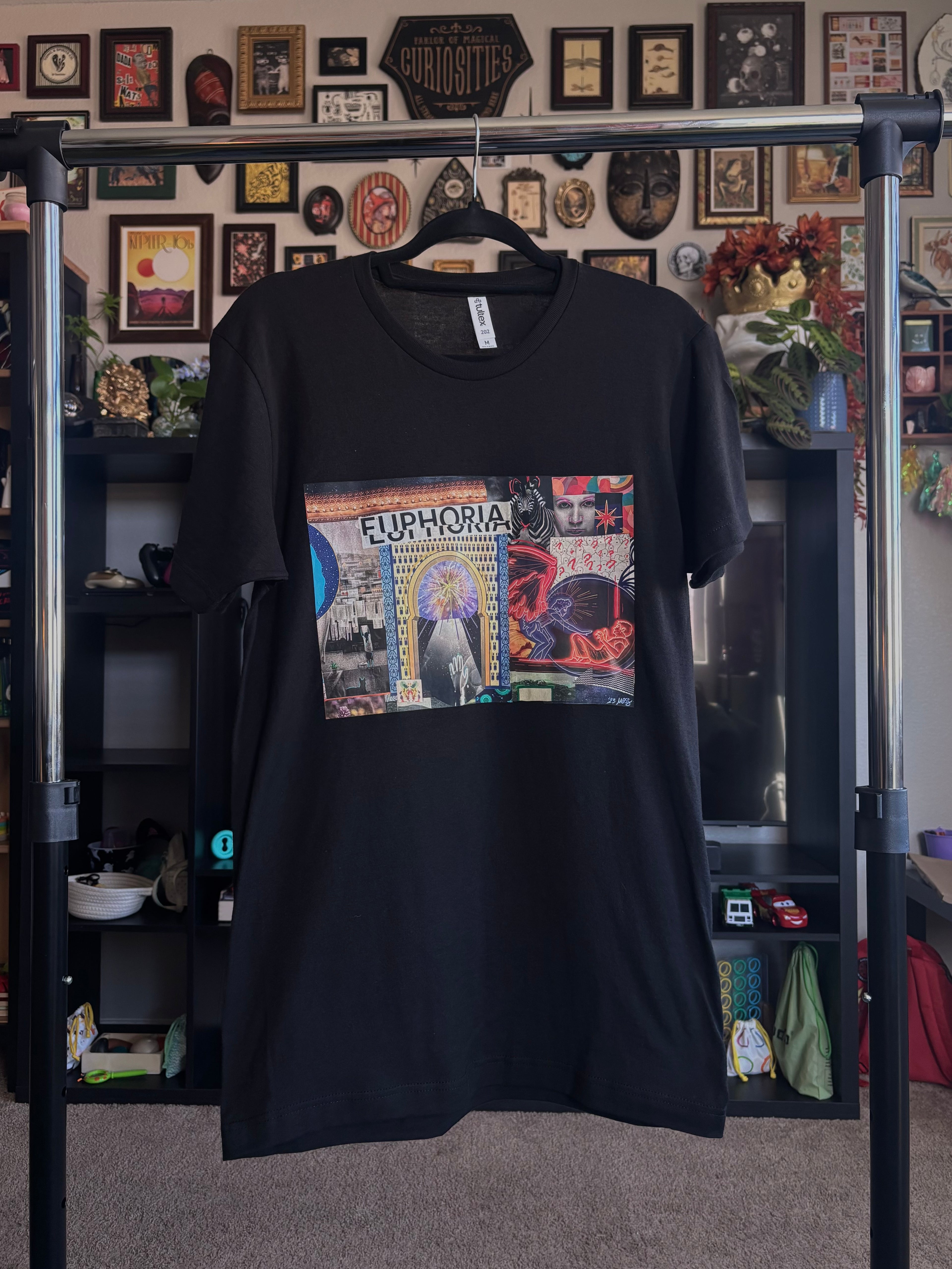 black t-shirt with a colorful graphic design of the EUPHORIA collage printed across the chest, hanging on a rack