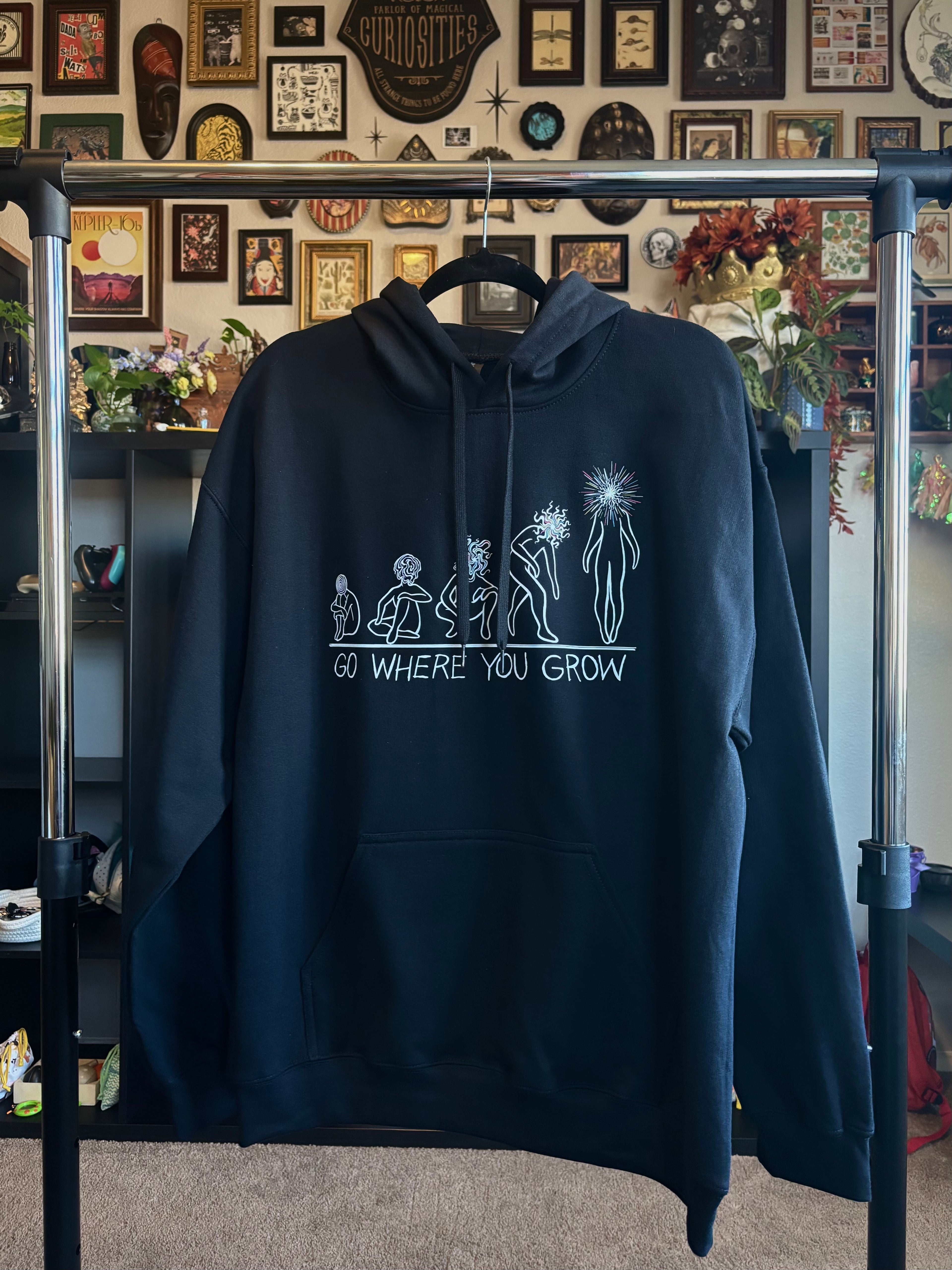 black hoodie with a graphic design showing the evolution of a soul as it transforms into a Star Child, with the text 'GO WHERE YOU GROW' printed across the chest
