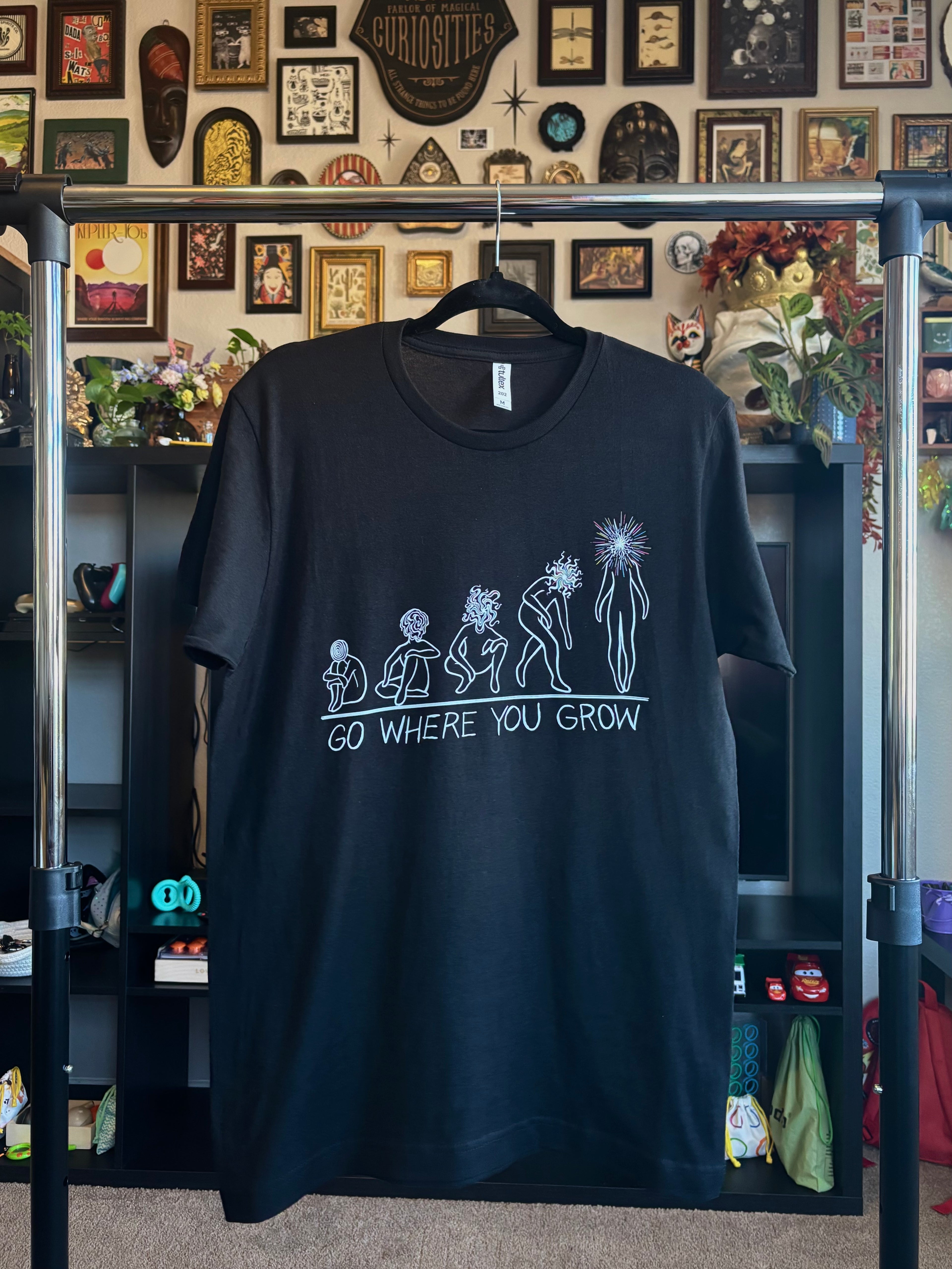 black t-shirt with a graphic design showing the evolution of a soul as it transforms into a Star Child, with the text 'GO WHERE YOU GROW' printed across the chest