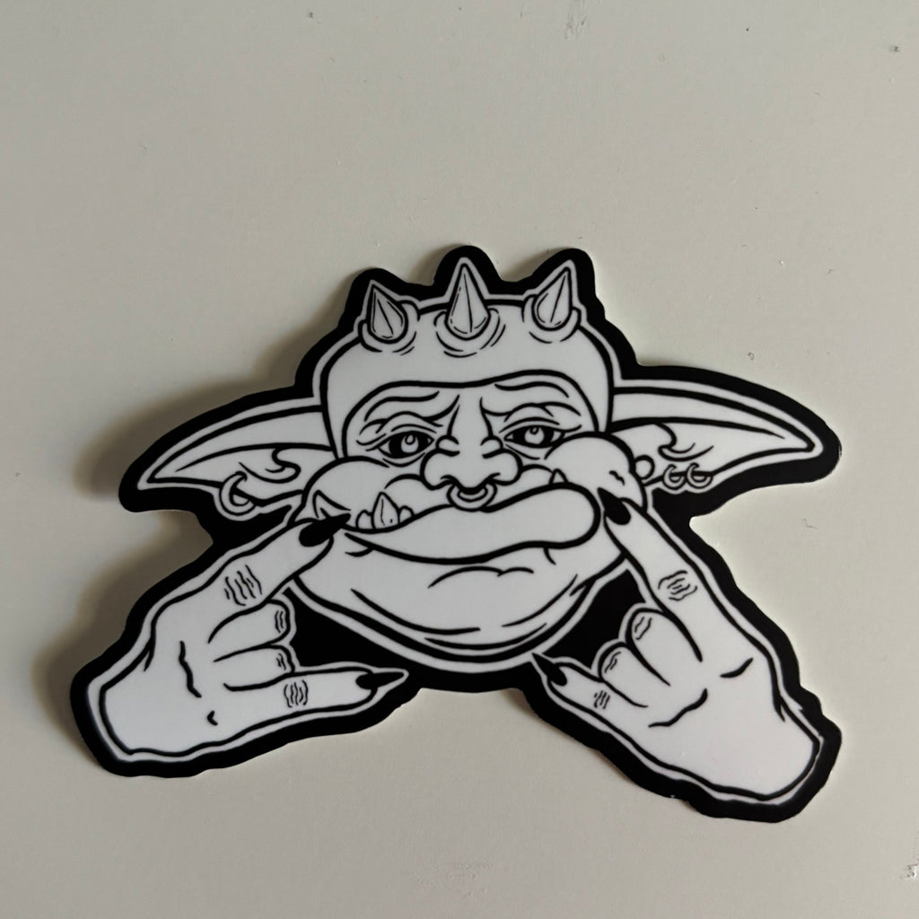 black and white sticker showing a goblin's face as he holds his hands up in the "rock on" gesture