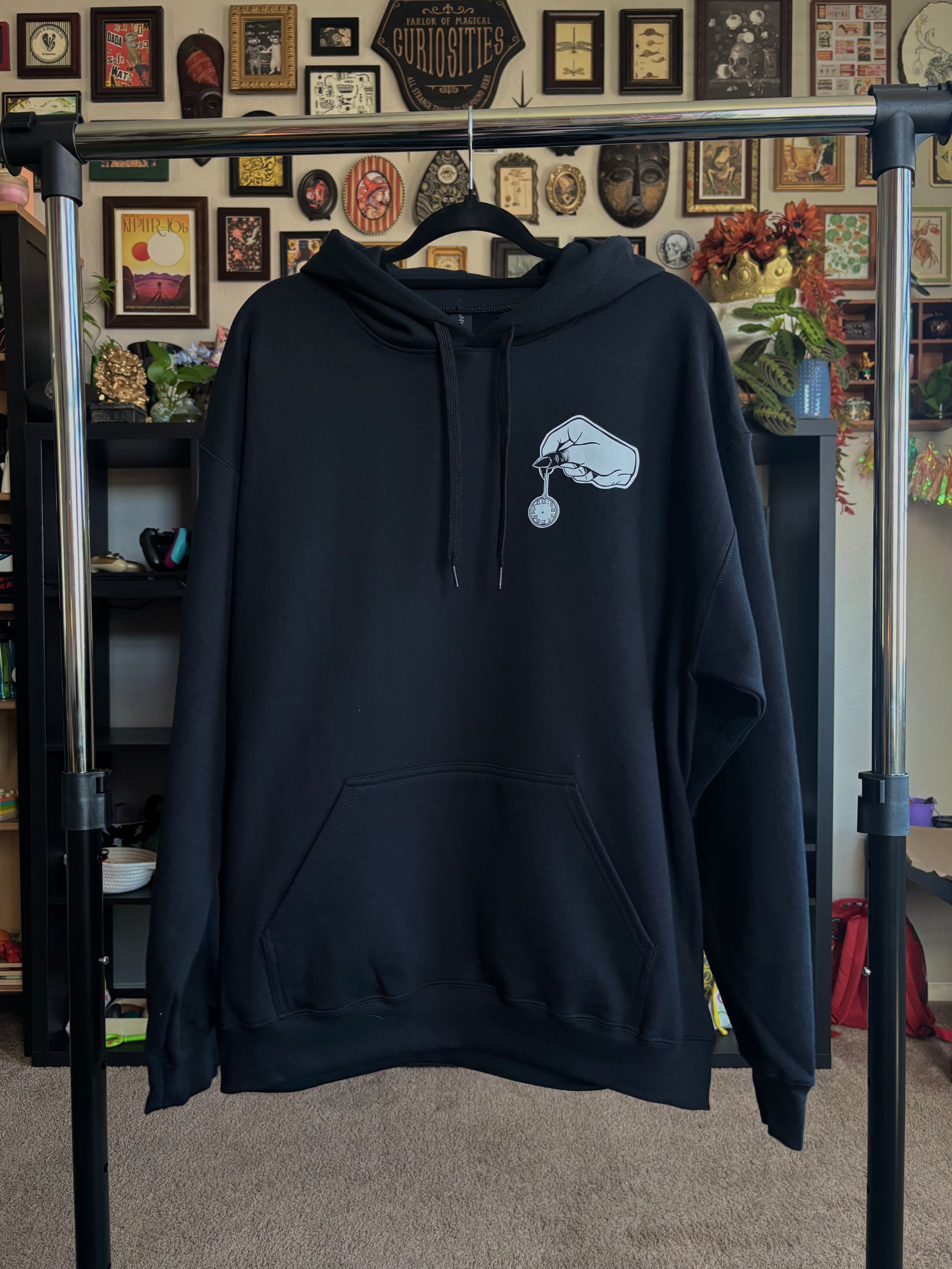 black hoodie with a club patch showing a spooky hand holding a small pocket watch