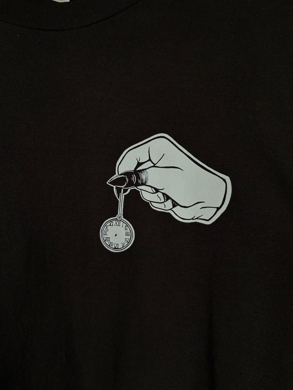 closeup look at the club patch on the front of the Killing Time design, which shows a hand with blackened fingers holding a small pocket watch