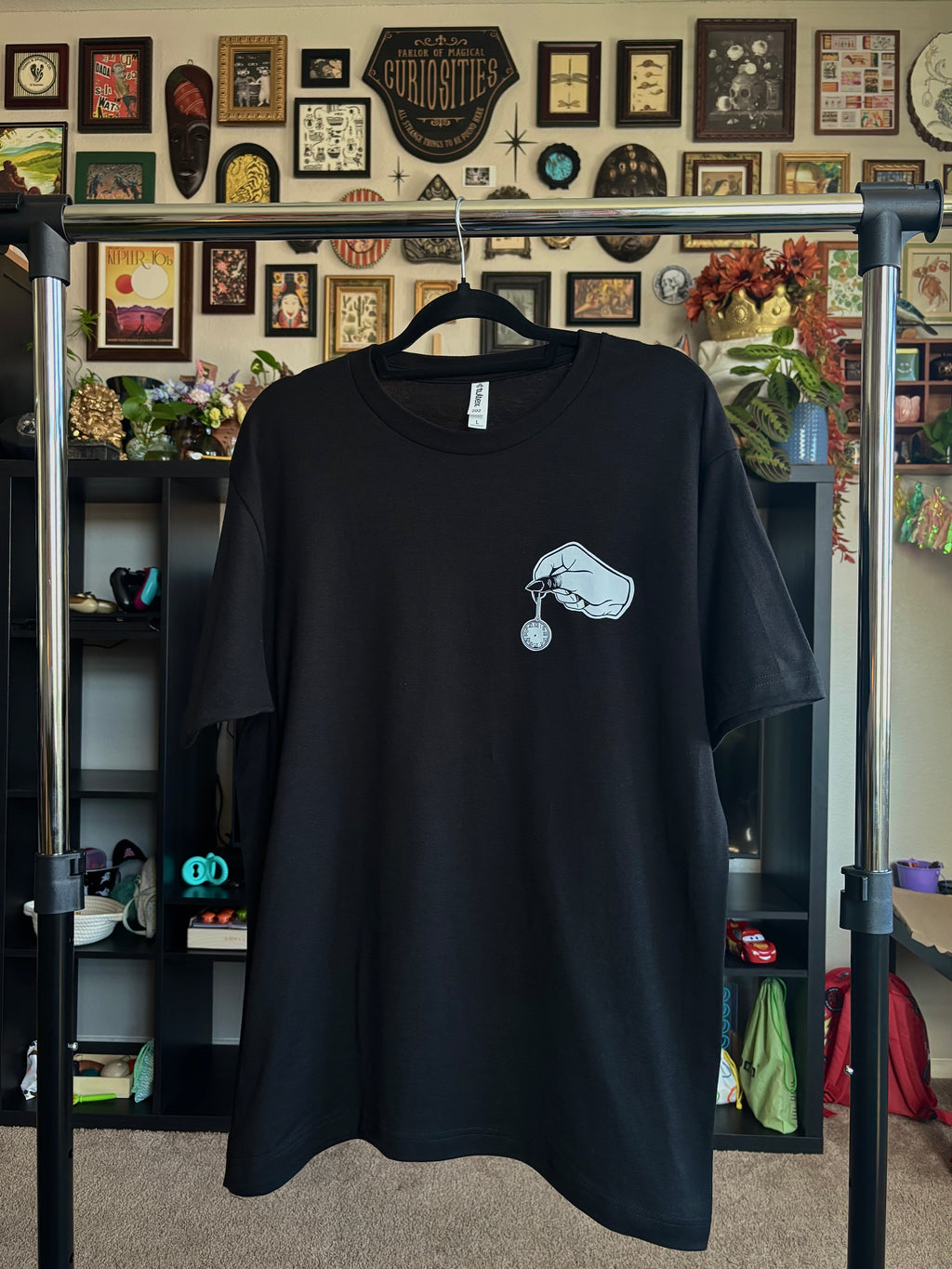 black tee with a club patch showing a spooky hand holding a small pocket watch