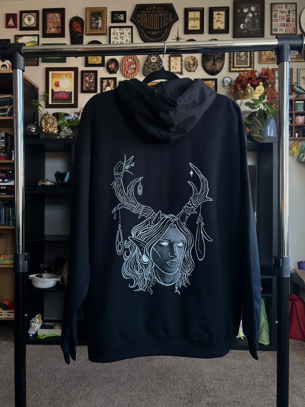 black hoodie hanging on a rack to display the King of the Forest, a Celtic inspired fae lord, printed across the back