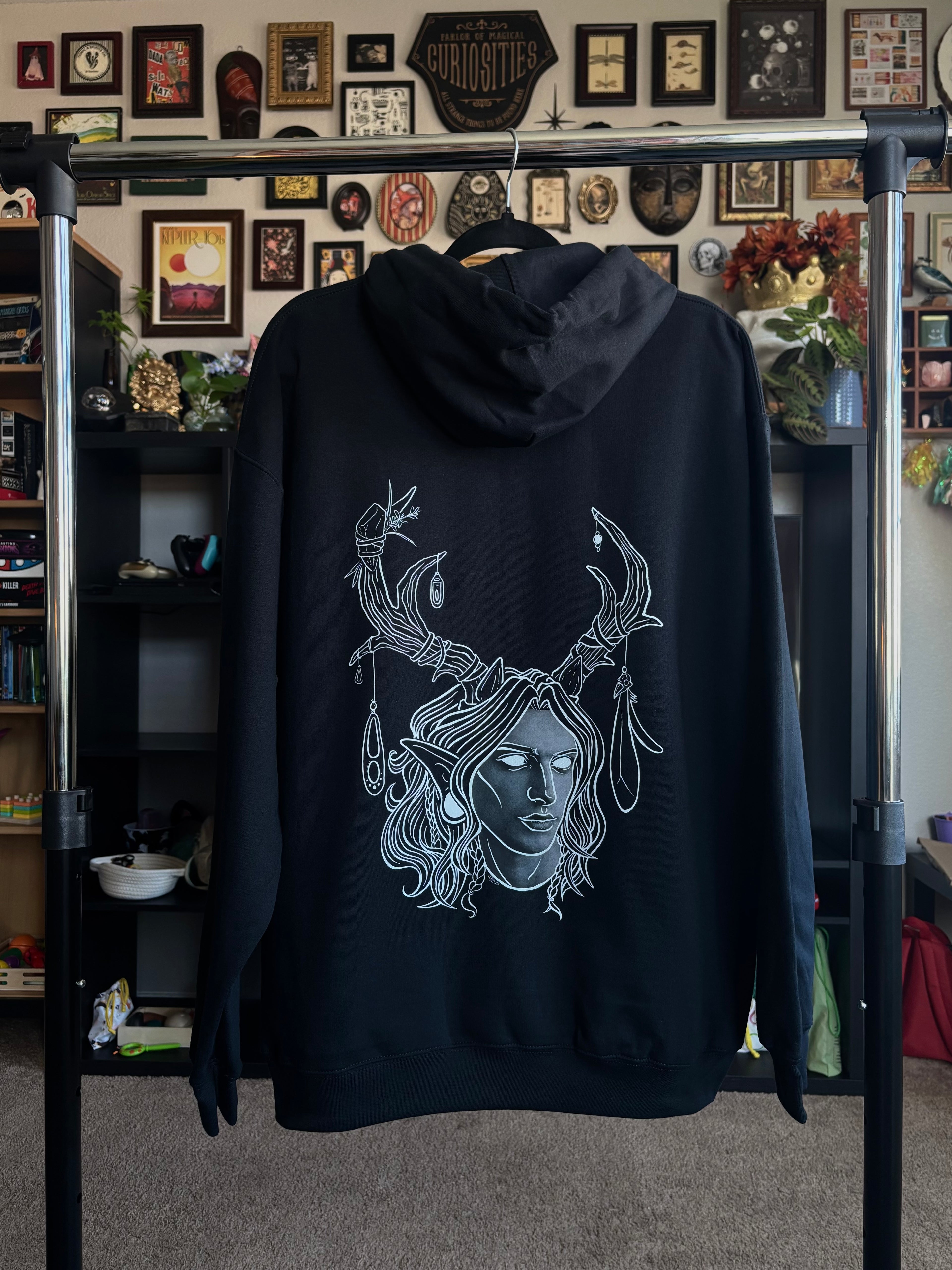 black hoodie hanging on a rack to display the King of the Forest, a Celtic inspired fae lord, printed across the back