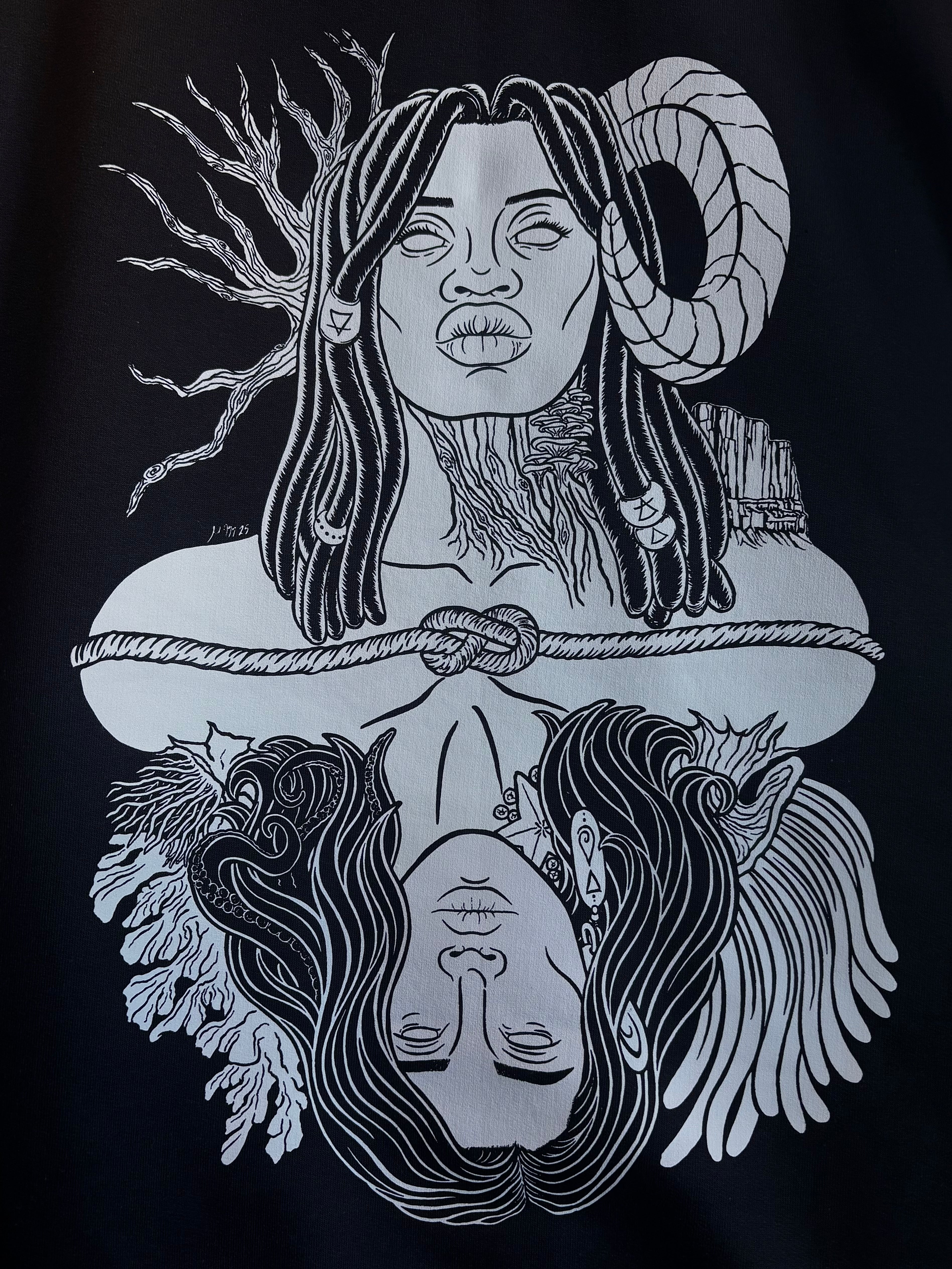 closeup look at the graphic design of Gaia, a powerful goddess adorned with beaded braids, a ram's horn, trees and mountains, who is connected to Oceanus, a god surrounded by coral and anemones with tentacles in his hair and a starfish and barnacles clinging to his neck, printed on the back of a black hoodie