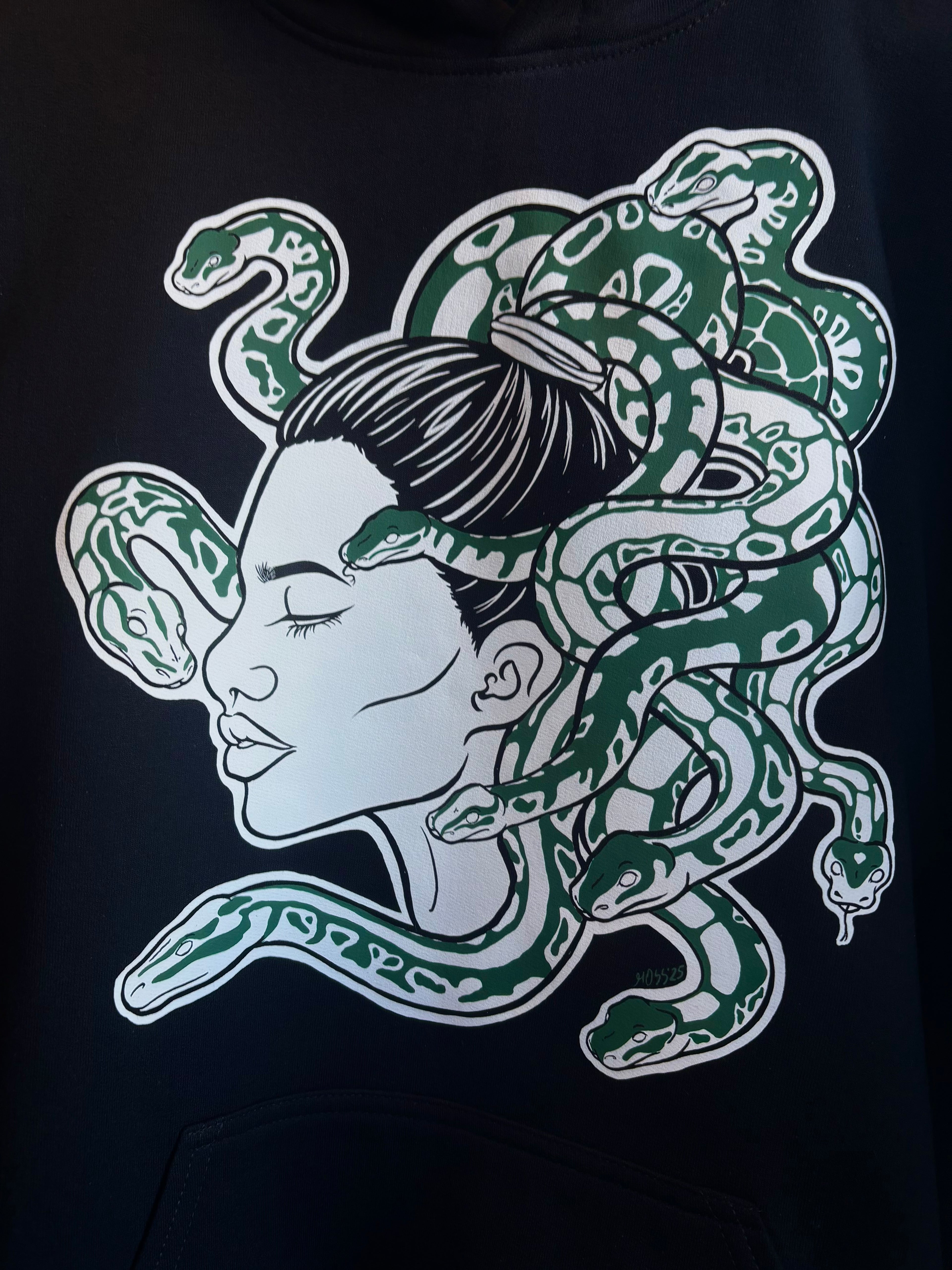 closeup look at the Medusa print on the front of a black hoodie