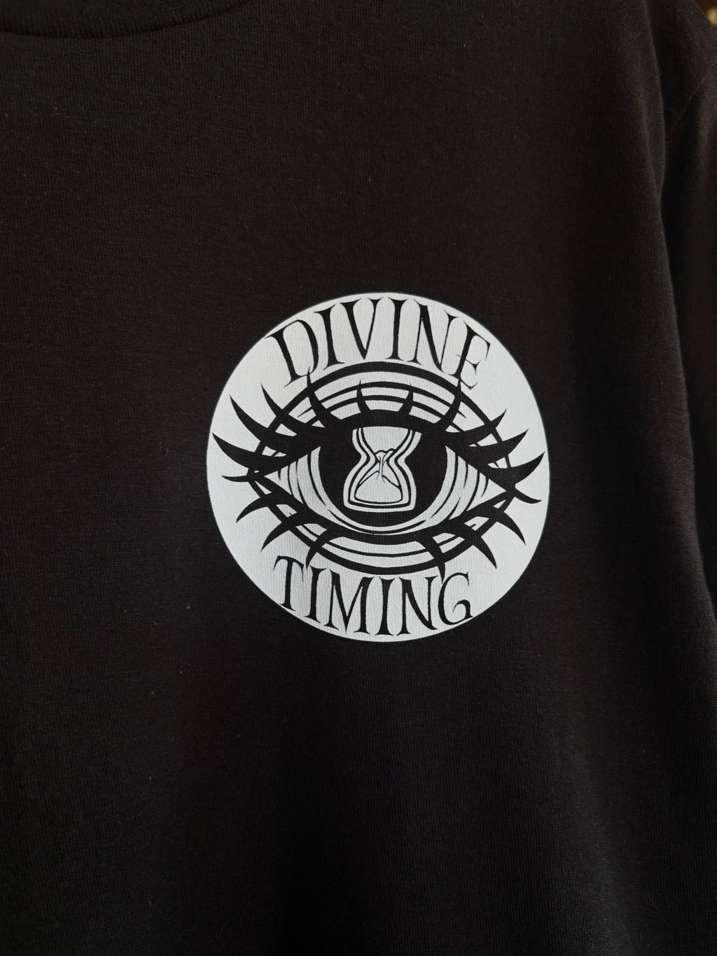 closeup look at the Divine Timing Hourglass Eye printed on the front of a black tee as a club patch