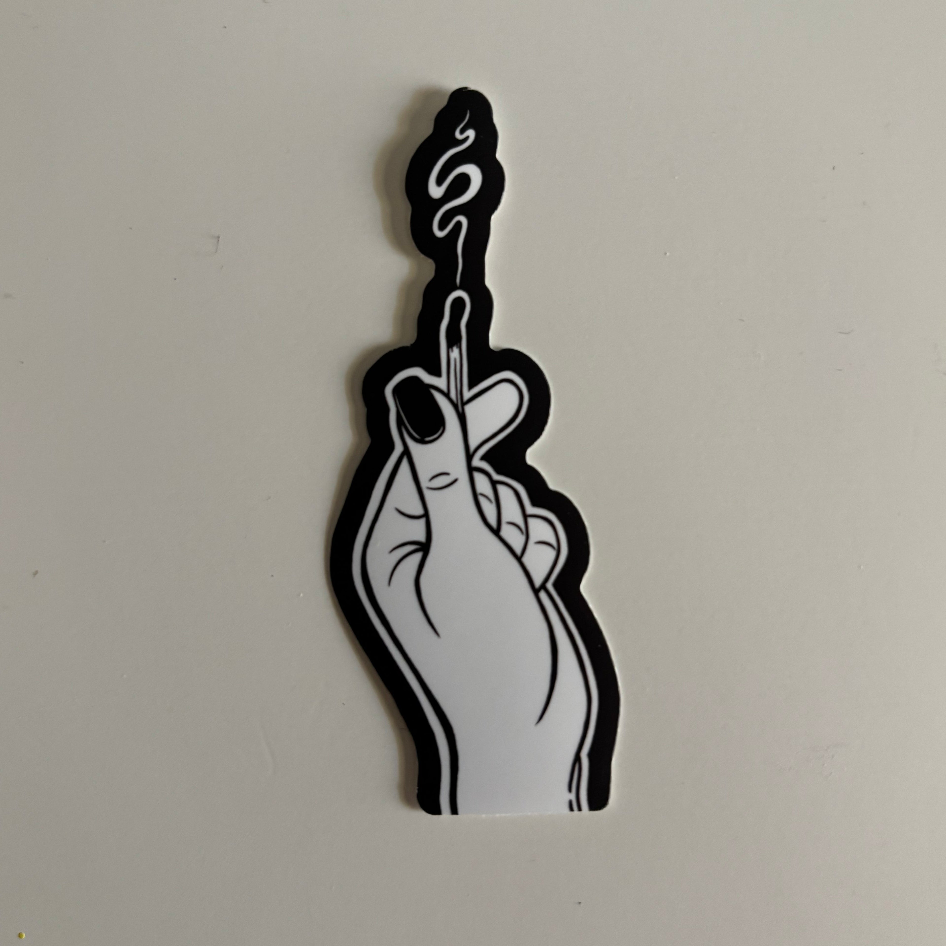 a black and white sticker of a hand holding a burnt out match, smoke curling up from the blackened end.